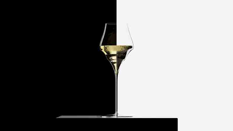 Sensorik Champagnerglas mit dem charakteristischen rautenförmigen, gewinkelten Kelch, gefüllt mit einer hellgelben Flüssigkeit, die feine Bläschen (Perlage) zeigt.